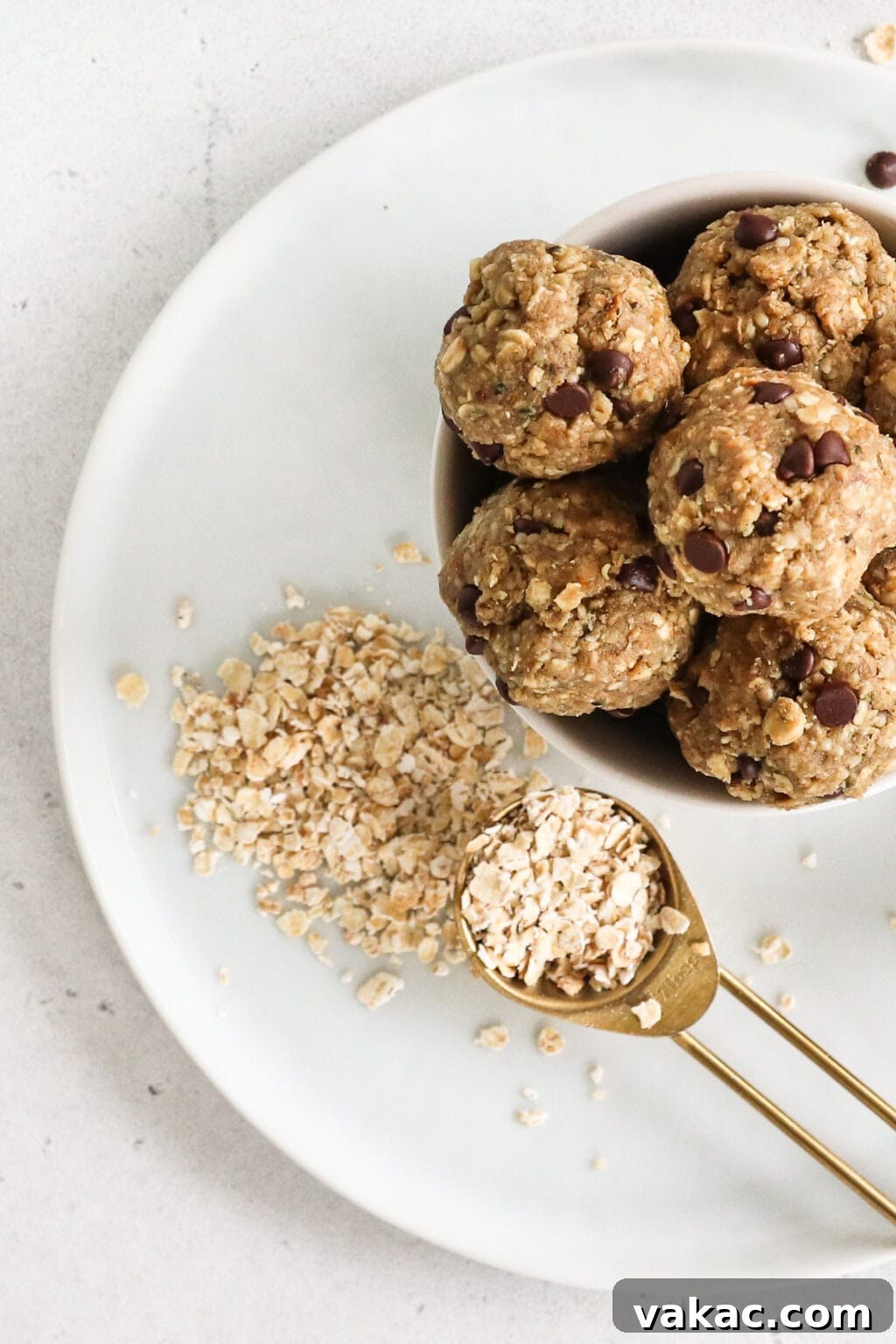 Easy Homemade Oat Flour in Minutes 2 A tablespoon of oats is beside a bowl of energy bites, both on a white plate. This image signifies the healthy and versatile uses of homemade oat flour in recipes like energy bites.