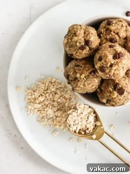 A tablespoon of oats is beside a bowl of energy bites, both on a white plate. Homemade oat flour can be used in many healthy recipes.