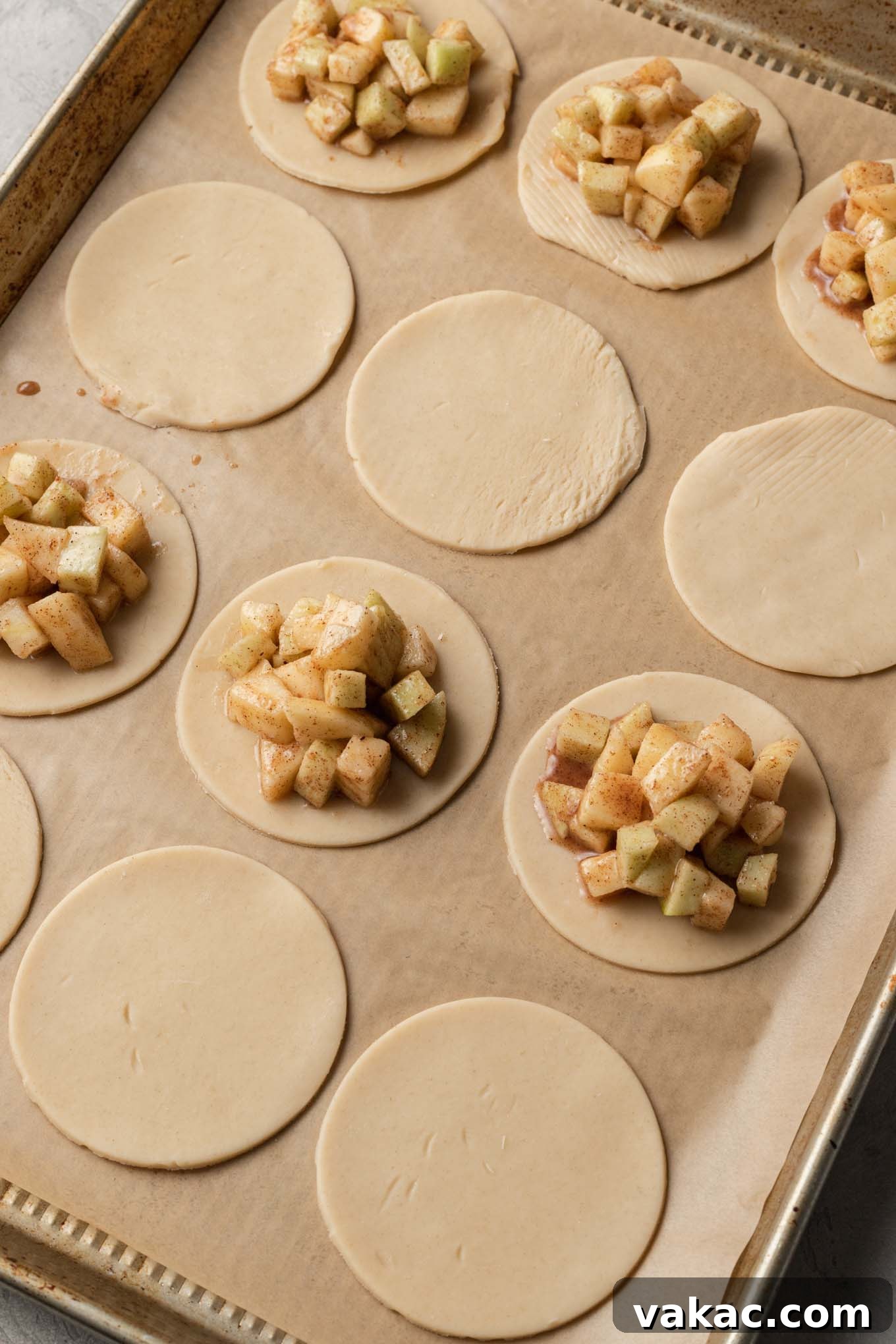 Golden Apple Pocket Pies 5 A process shot showing several perfectly cut circles of pie dough, half of them generously filled with the spiced apple mixture, awaiting their top crusts.