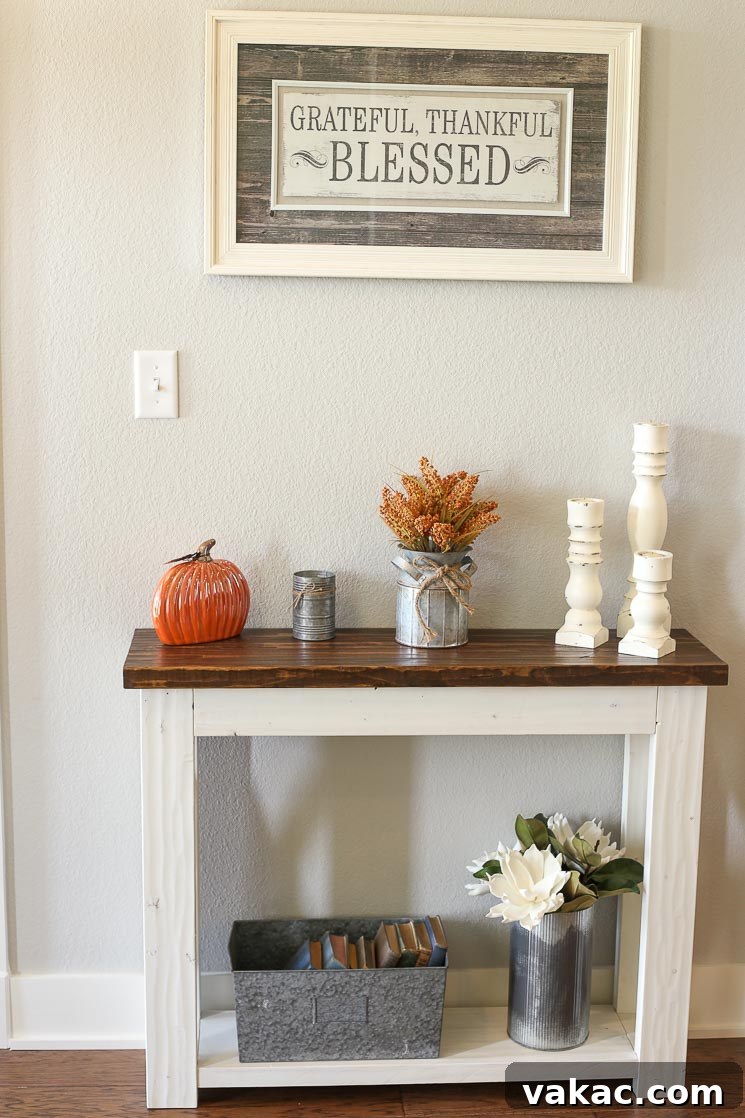 Our New Home Tour and Life Lately 11 A charming farmhouse-style entry table with distressed wood finish, adorned with rustic decor, set against a light gray wall in an inviting entryway.