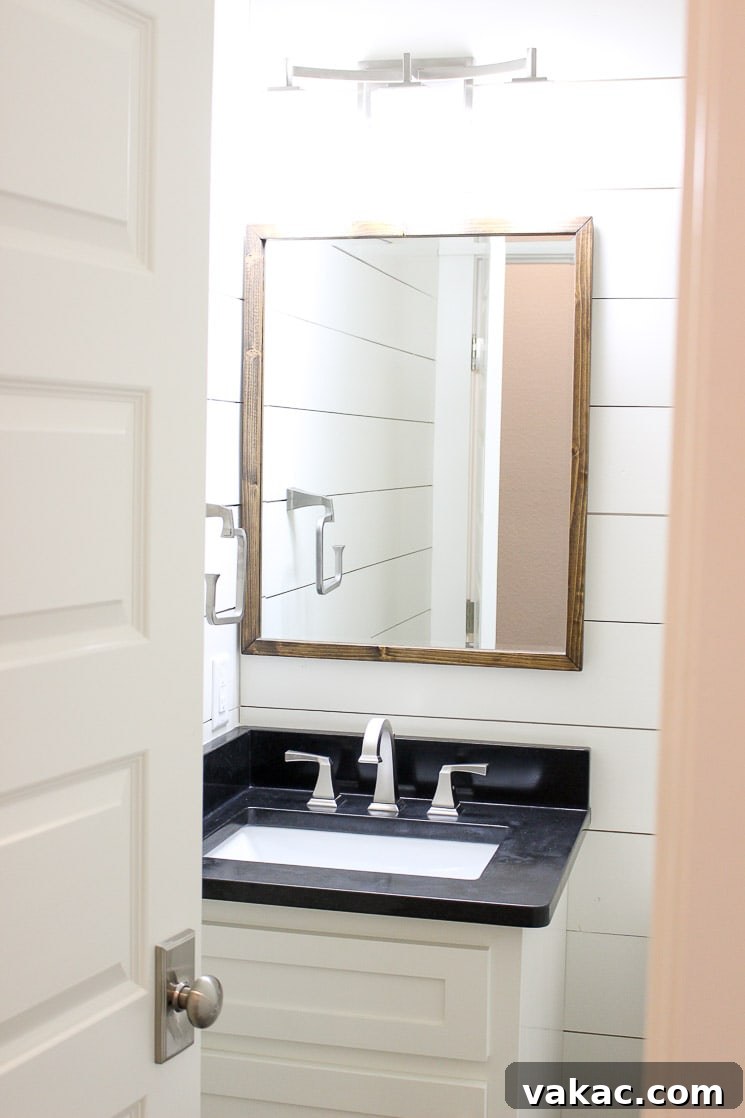 Our New Home Tour and Life Lately 14 A stylish half bathroom showcasing pristine white shiplap walls, sleek black granite countertops, and a modern vanity, awaiting decorative accents.
