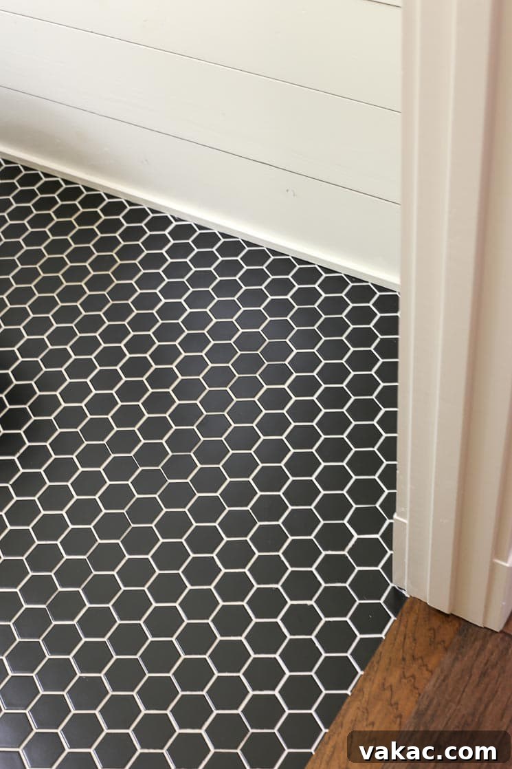 Our New Home Tour and Life Lately 15 A striking half bathroom floor featuring black hexagonal tiles with crisp white grout, complemented by elegant white shiplap walls for a modern farmhouse aesthetic.