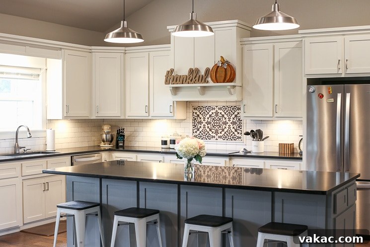 Our New Home Tour and Life Lately 3 A pristine kitchen featuring white shaker cabinets, sleek black honed granite countertops, a spacious gray island, and modern pendant lighting.