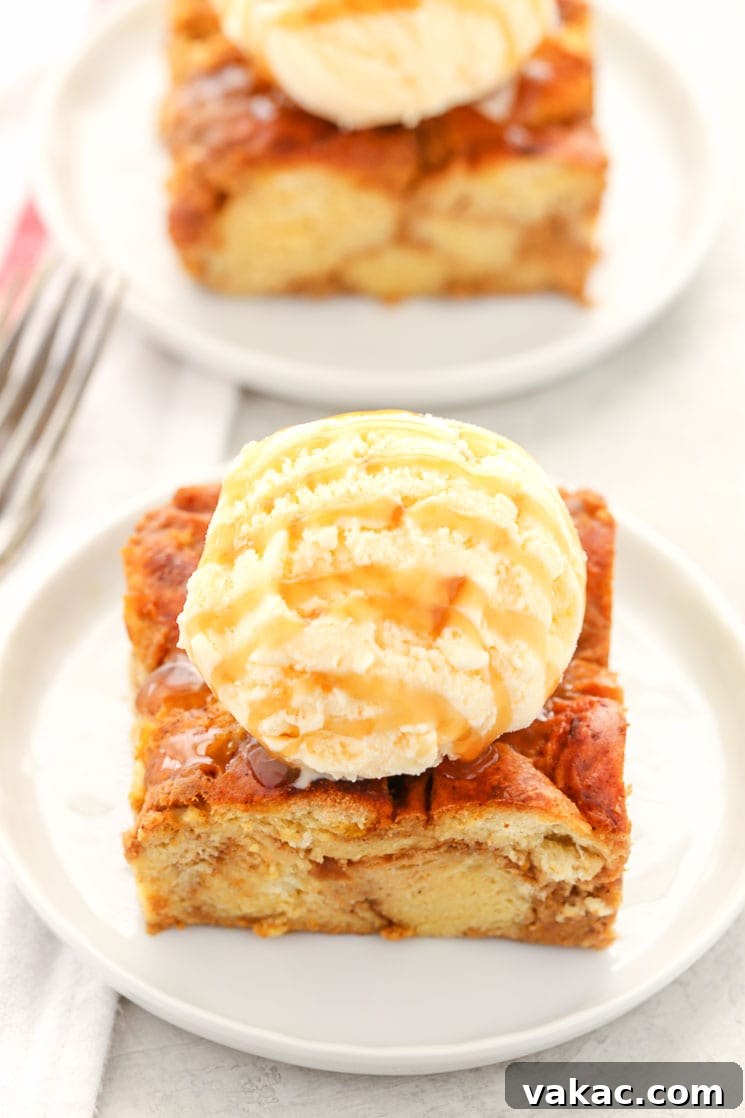 Two generous slices of warm pumpkin bread pudding, beautifully topped with a scoop of creamy vanilla ice cream and a drizzle of rich caramel sauce, resting on elegant white plates.