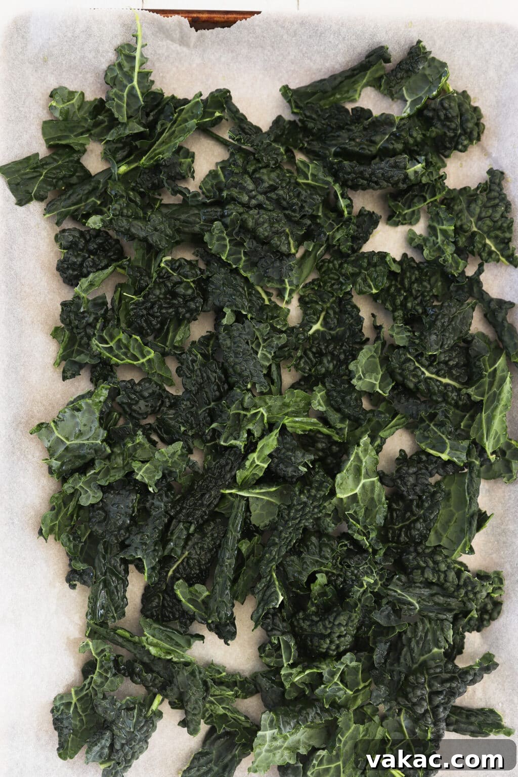 Quick Comfort: 4-Ingredient Warm Kale & Toasted Coconut Salad 6 Placing torn kale leaves onto a parchment-lined baking sheet.