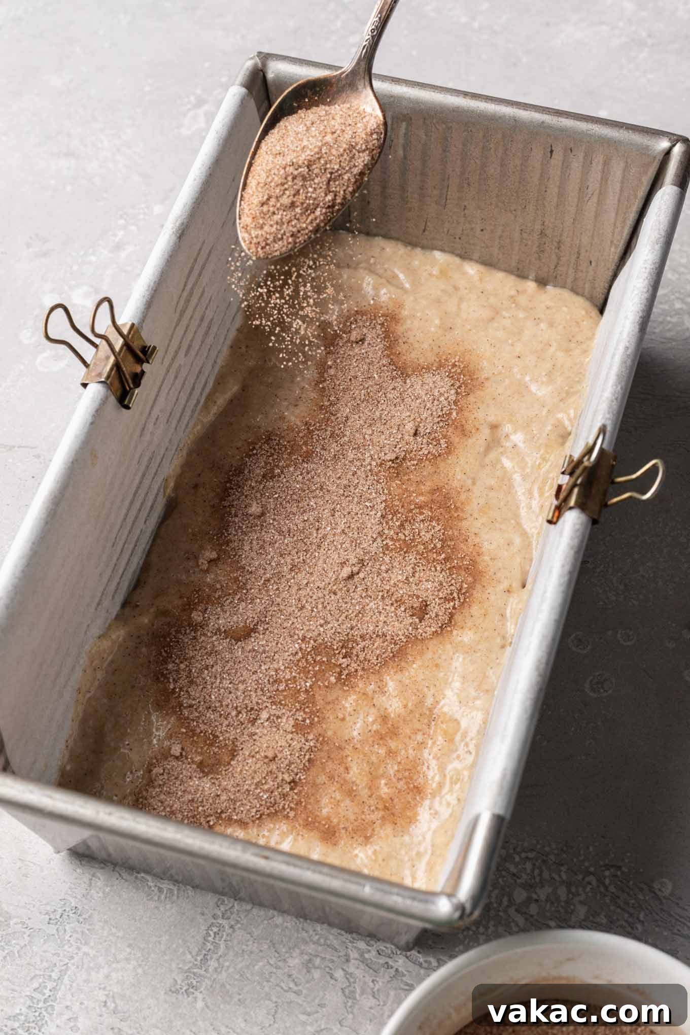 Marbled Cinnamon Banana Loaf 6 Banana bread batter in a loaf pan with cinnamon and sugar sprinkled on top, ready for more batter.