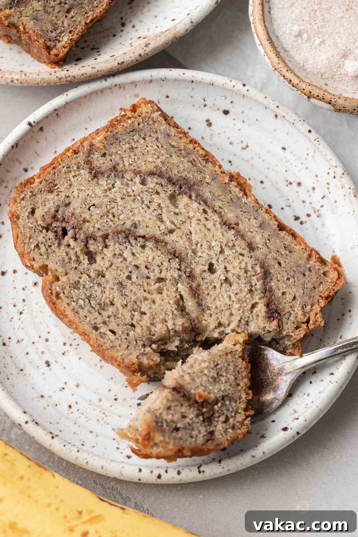Marbled Cinnamon Banana Loaf 10 A close up view of a slice of cinnamon banana bread on a dessert plate, showcasing the texture and swirl.
