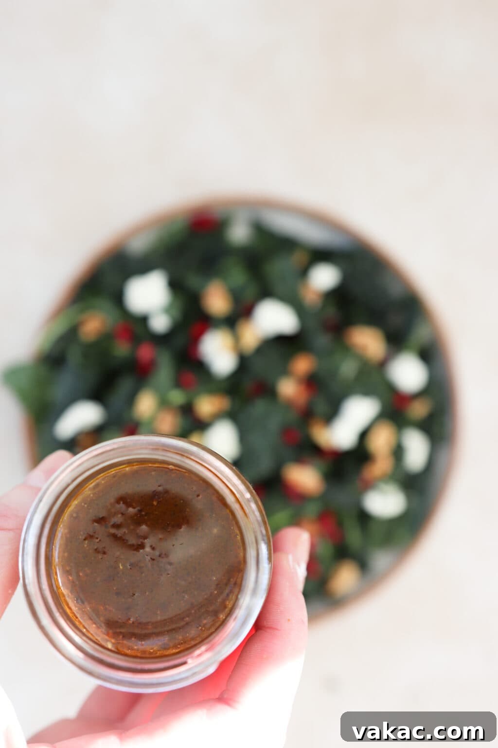 A finished kale and pomegranate salad, evenly dressed and ready to be tossed and served.