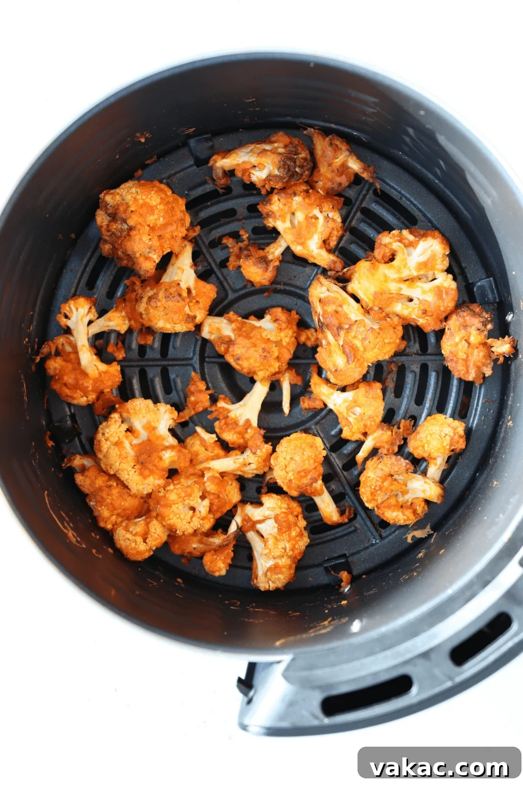Air Fryer Buffalo Cauliflower Nuggets 5 An air fryer has buffalo and panko coated cauliflower evenly spread out in it.