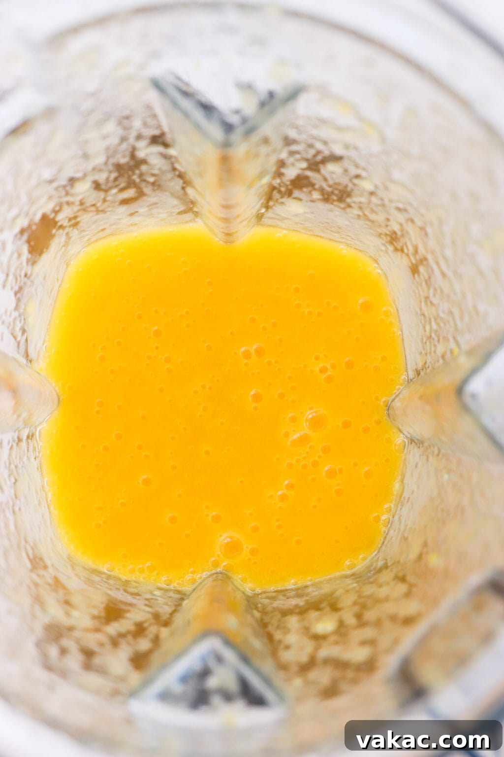 Effortless Wholesome Mango Puree 5 An overhead shot of a blender filled with a smooth, yellowish-orange mango puree after blending.