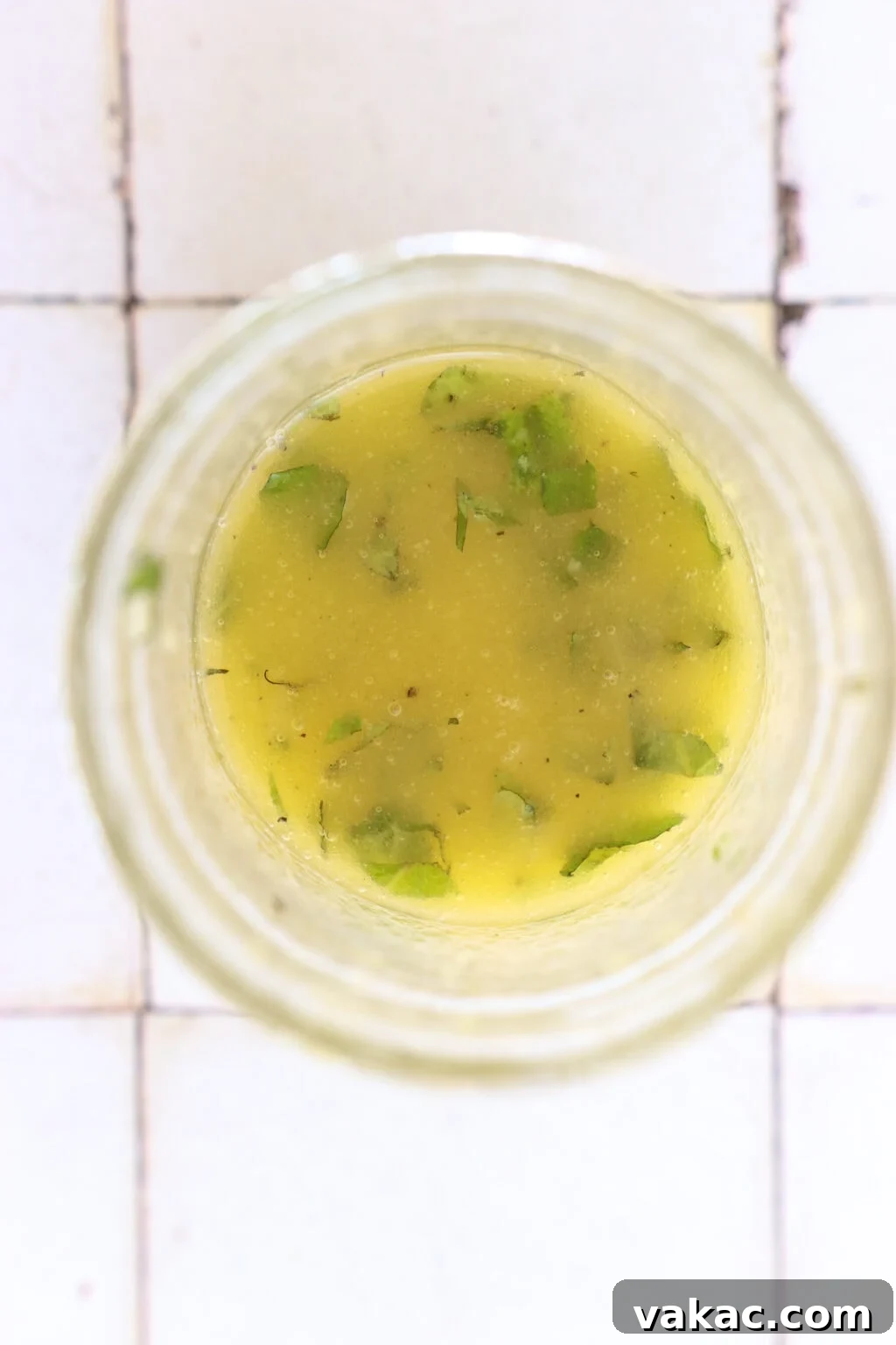 Zesty 5-Minute Mango Mint Vinaigrette 5 An overhead shot of a glass bowl on a white tile counter, now with emulsified mango and mint salad dressing, perfectly blended and smooth.