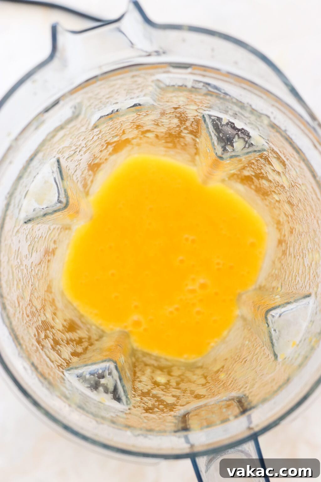 Sweet Heat Mango Tajin Popsicles 4 An overhead shot captures a high-speed blender actively mixing an orange-yellow liquid, creating a bubbling, smooth consistency.