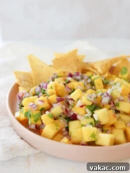 A vibrant pink plate filled with Mango Habanero Salsa and tortilla chips, ready for serving.
