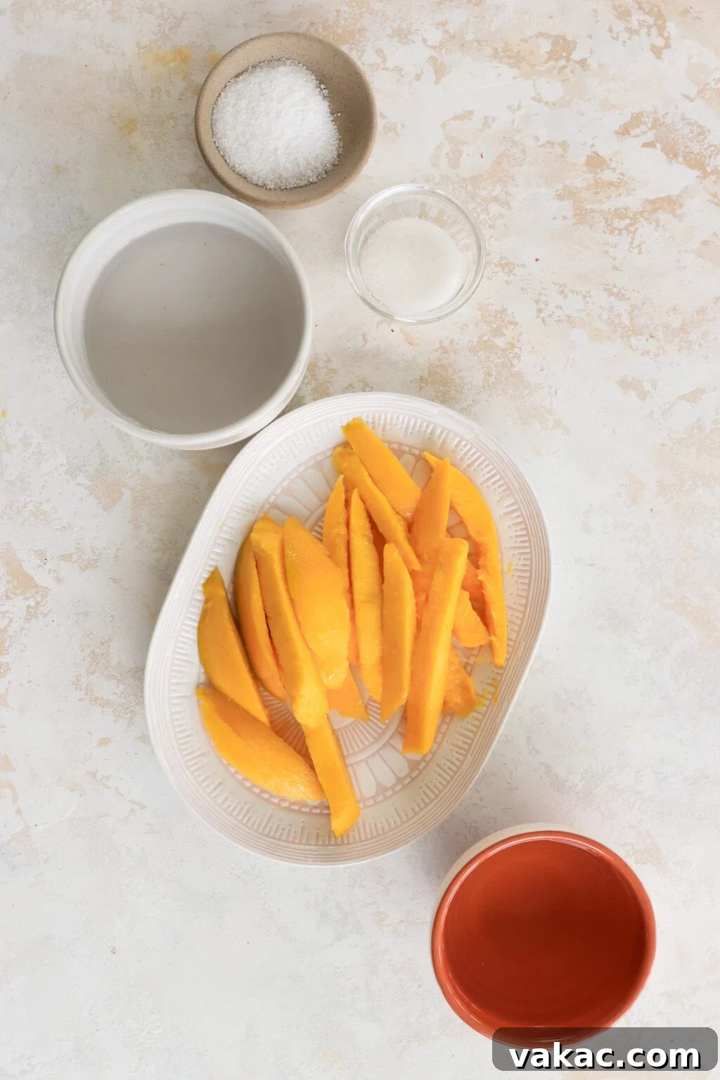 Easy Quick Pickled Mango Recipe 3 An overhead shot showcasing the four essential ingredients for making quick pickled mango: sliced mango, white wine vinegar, sugar, and salt, artfully arranged on a clean surface.