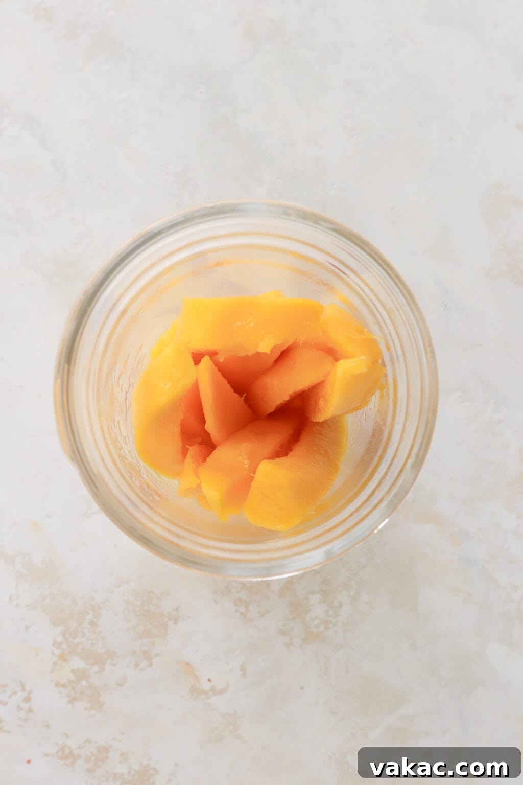 Easy Quick Pickled Mango Recipe 8 An overhead view of a clear mason jar, neatly packed with about ten vibrant mango slices, ready for the pickling liquid.