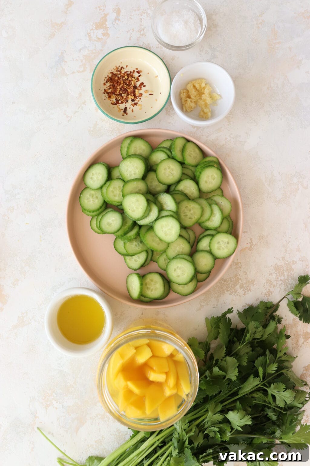 Bright Bites: 5-Minute Mango and Cucumber Salad 3 An overhead shot showcasing the fresh ingredients for the salad, including sliced mini cucumbers, a jar of pickled mango, fresh cilantro, olive oil, and small bowls of red pepper flakes and minced garlic.