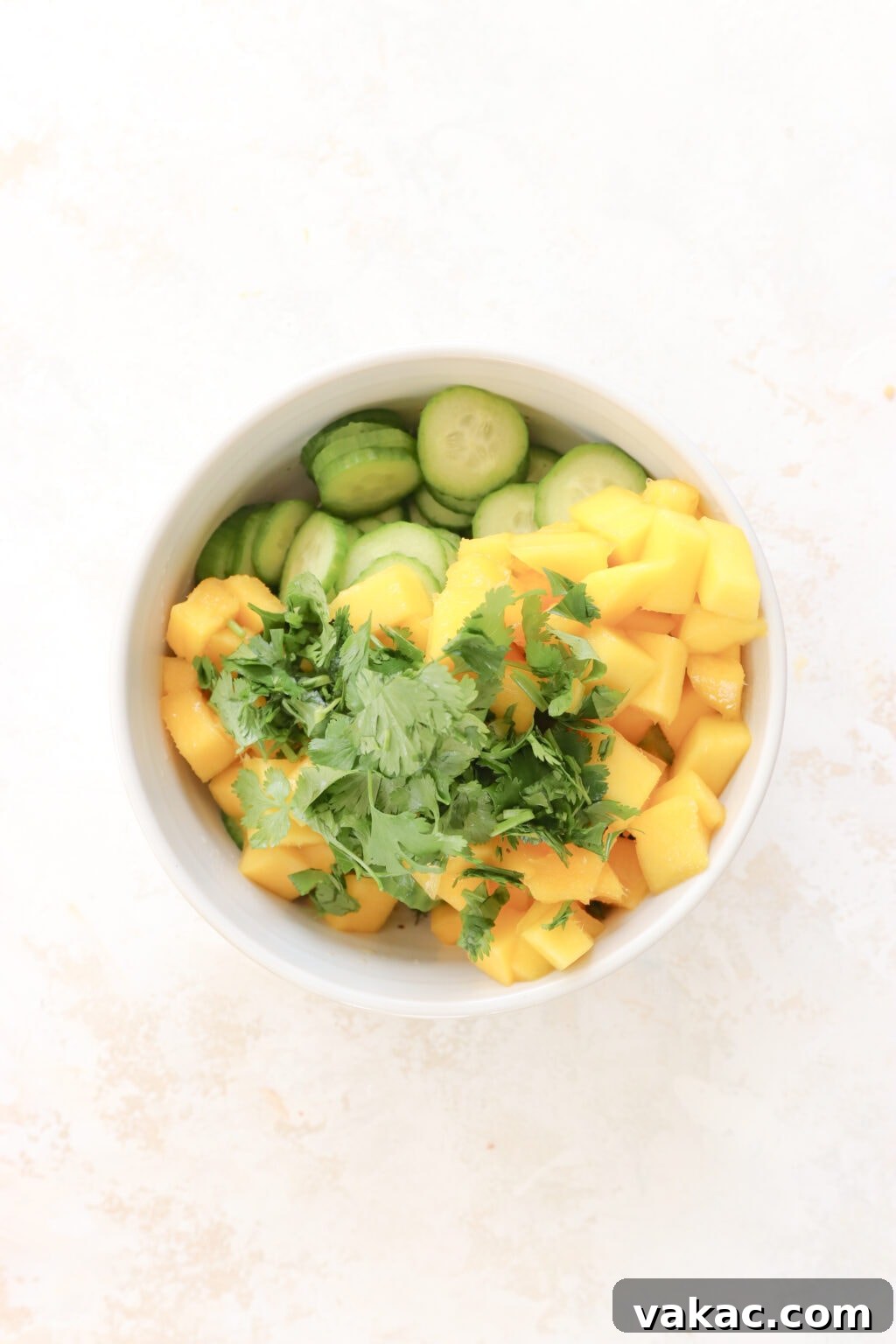 Bright Bites: 5-Minute Mango and Cucumber Salad 5 A white bowl brimming with the colorful components of the salad: thinly sliced cucumber, perfectly diced pickled mango, and freshly chopped cilantro, awaiting the dressing.