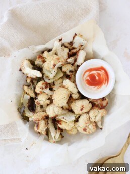 A parchment-lined bowl filled with roasted cauliflower and spicy yogurt.