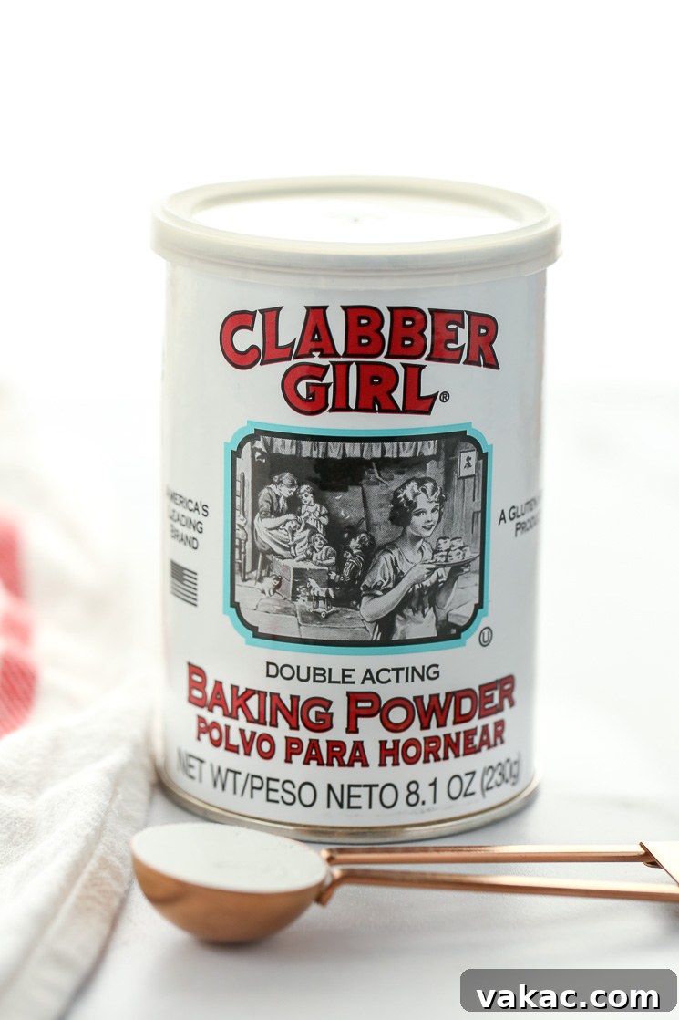 Kitchen Chemistry: Baking Soda vs. Baking Powder 4 A can of baking powder behind a measuring spoon sitting on top of a marble surface.