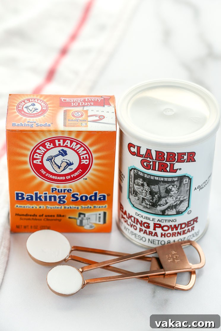 Kitchen Chemistry: Baking Soda vs. Baking Powder 5 A box of baking soda, can of baking powder, and measuring spoons sitting on top of a marble surface with a white napkin on the side.
