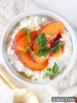 A bowl filled with cottage cheese and topped with fresh peach slices and mint.