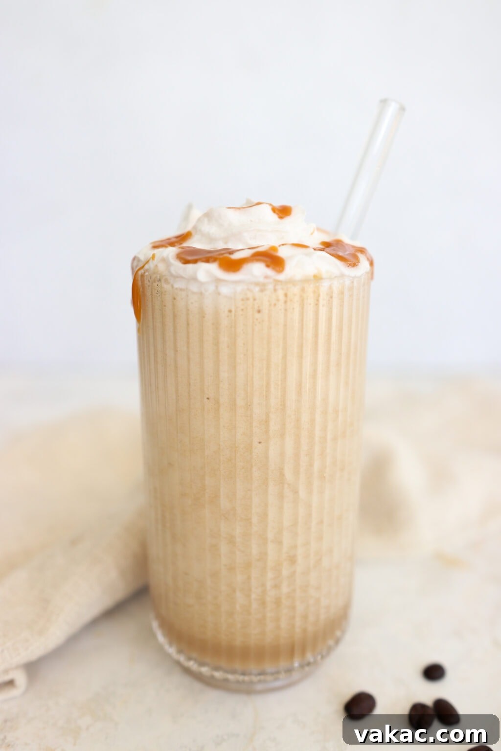 Protein Coffee Surge Smoothie 2 High protein coffee smoothie topped with whipped cream and caramel drizzle in a tall glass with a glass straw.