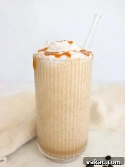 High protein coffee smoothie topped with whipped cream and caramel drizzle in a tall glass with a glass straw.