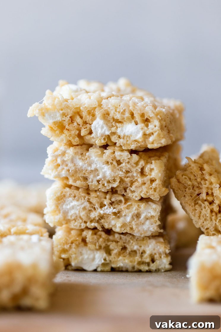 A stack of perfectly gooey Rice Krispie Treats on a rustic wooden tray, ready to be enjoyed.