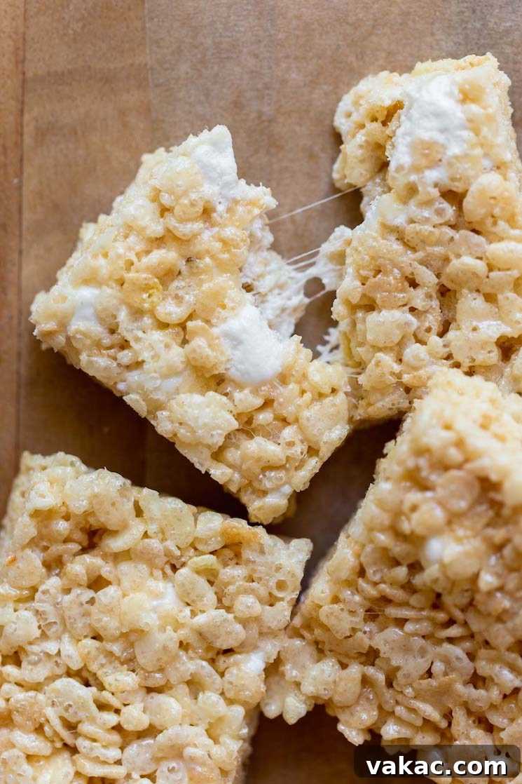 A close-up shot of a Rice Krispie Treat being pulled apart, revealing the deliciously gooey and stretchy marshmallow strands within.