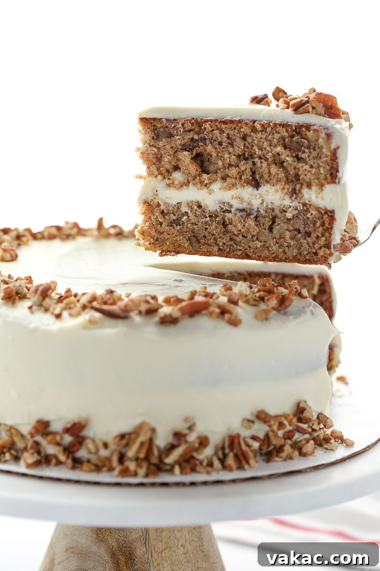 A magnificent whole hummingbird cake displayed on a sleek marble cake stand, with one slice carefully removed to reveal the exquisite layers and frosting within.