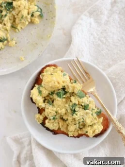 A piece of toast topped with spinach and pest cottage cheese scrambled eggs.