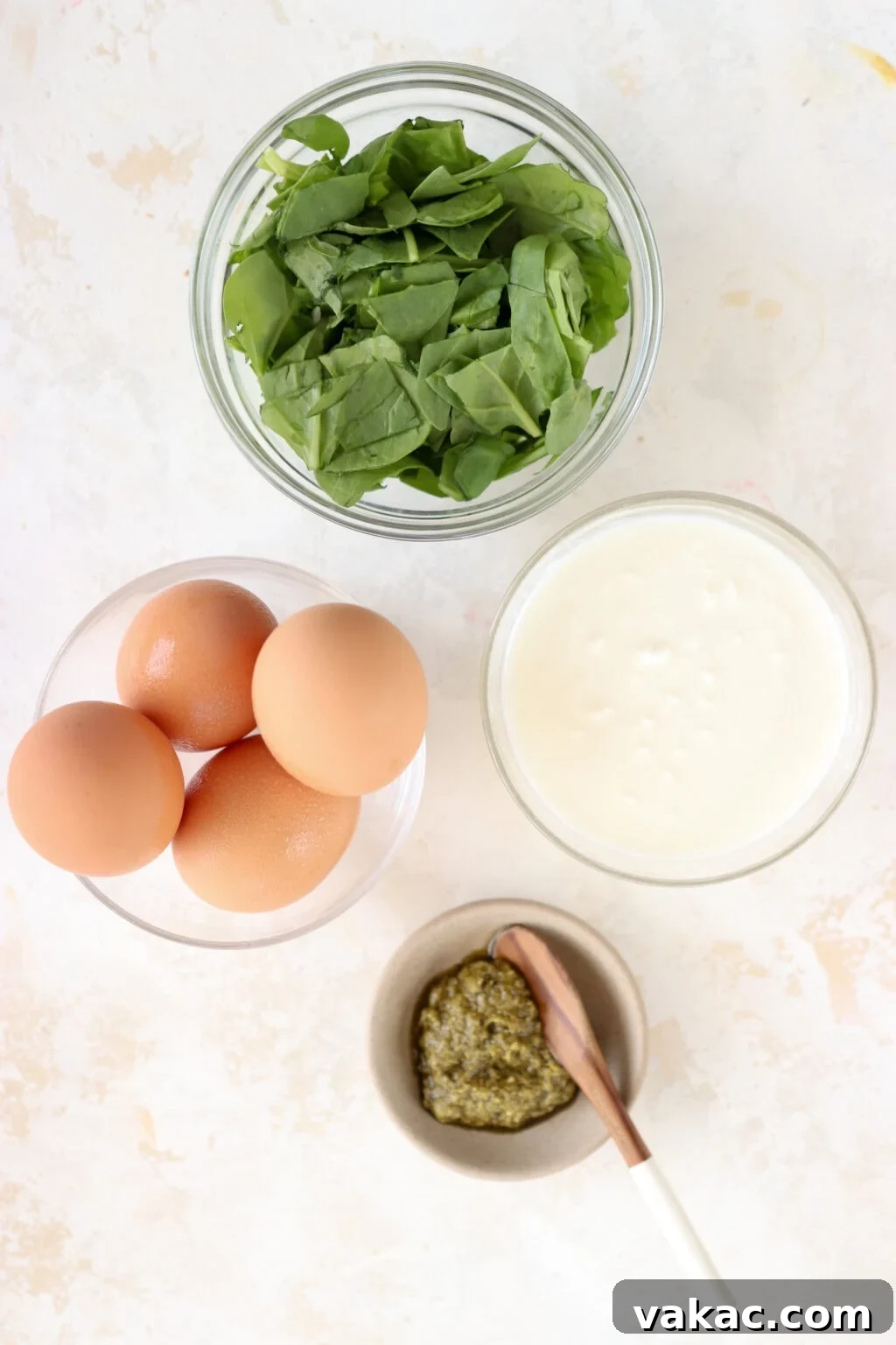 Dreamy 10-Minute Cottage Cheese Scramble 3 The fresh ingredients laid out artfully in small bowls, including vibrant green spinach, creamy white cottage cheese, fresh eggs, and rich green pesto, ready for cooking.