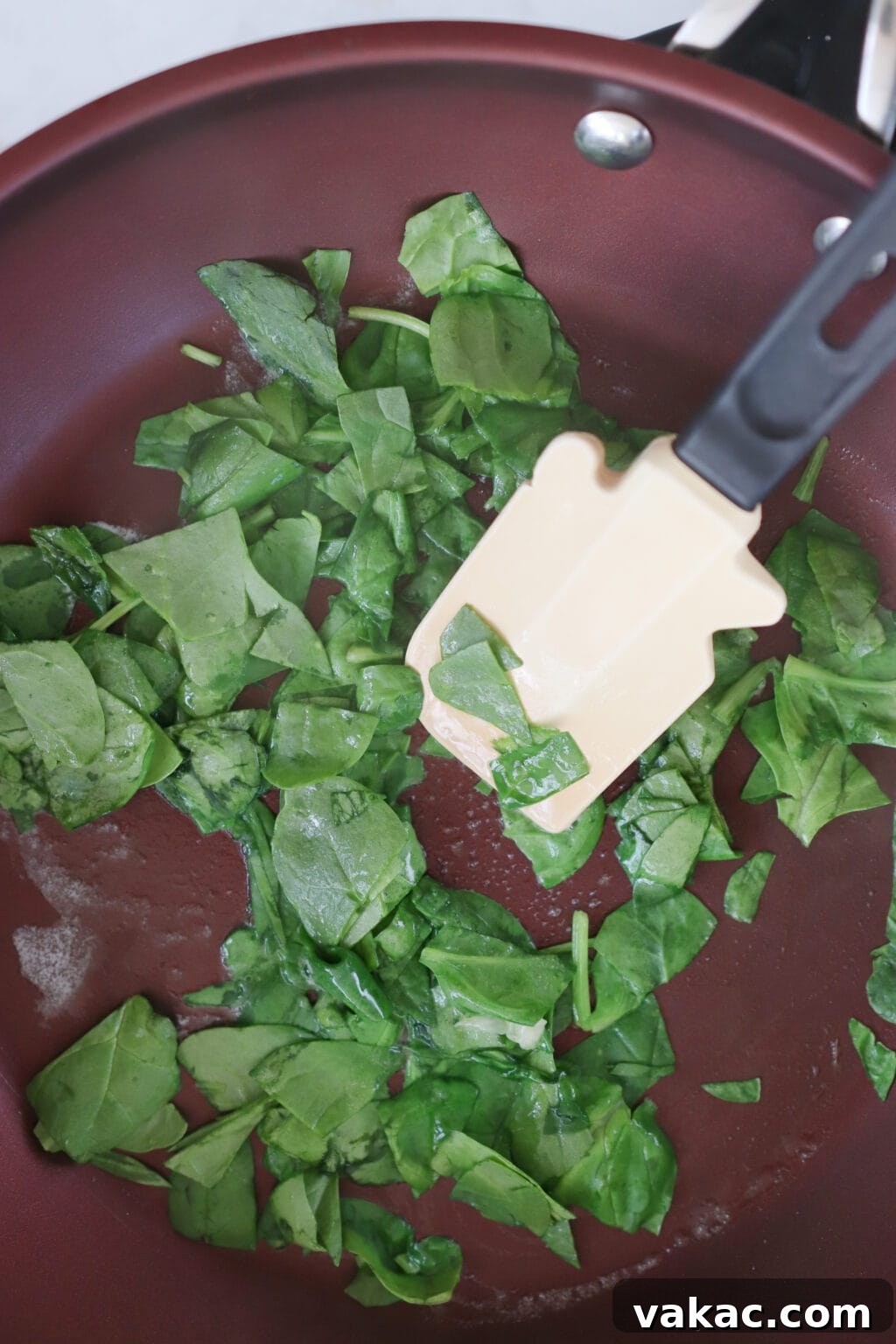 Dreamy 10-Minute Cottage Cheese Scramble 5 A non-stick frying pan heating on a stovetop, with a handful of fresh green spinach leaves gently wilting in a small amount of butter or oil.