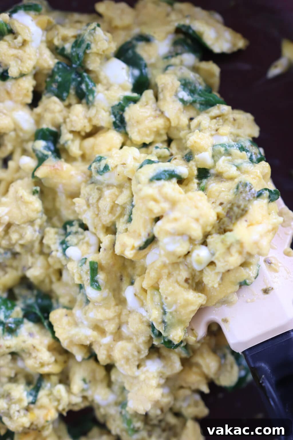 Dreamy 10-Minute Cottage Cheese Scramble 7 Perfectly cooked scrambled eggs with spinach still in the frying pan, appearing almost set but retaining a slight glistening wetness, indicating they are ready for the final step.
