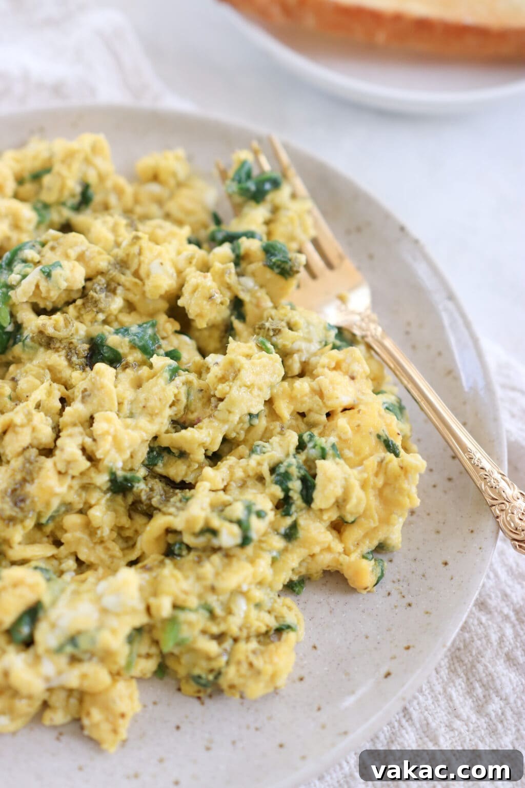 Dreamy 10-Minute Cottage Cheese Scramble 8 A plate of perfectly cooked scrambled eggs, vibrant green with spinach and pesto, ready to be enjoyed as a wholesome breakfast.