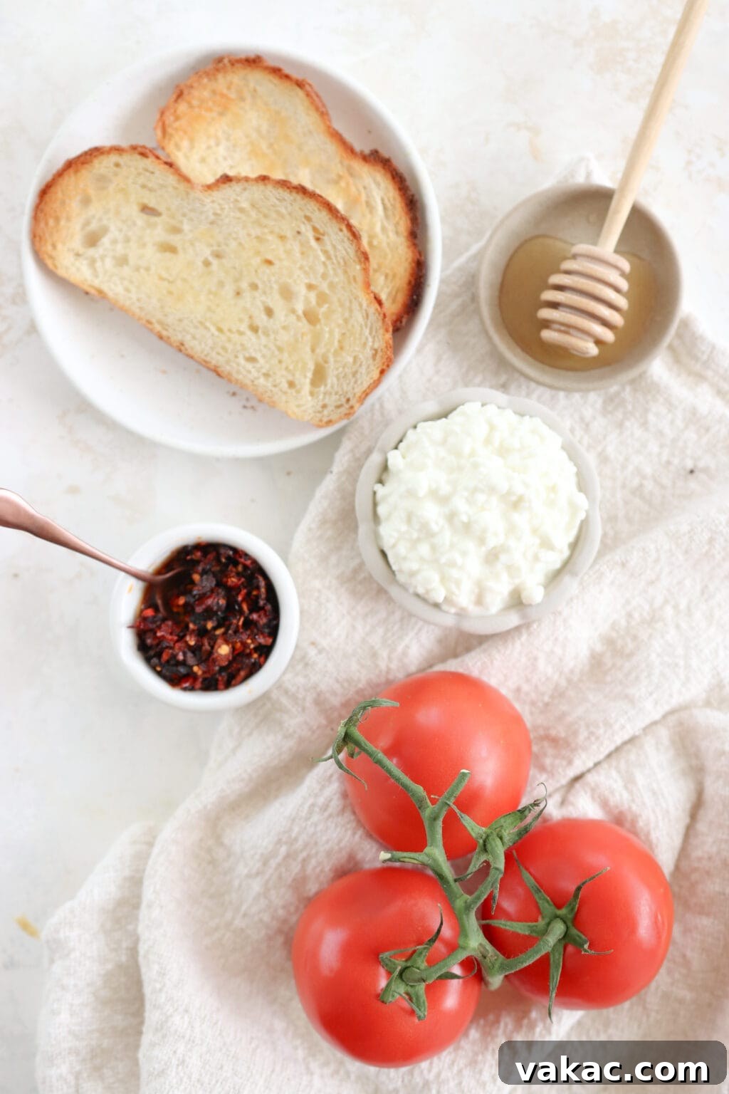 Ingredients for the recipe laid out include sourdough toast, honey, cottage cheese, chili crisp oil, and tomatoes