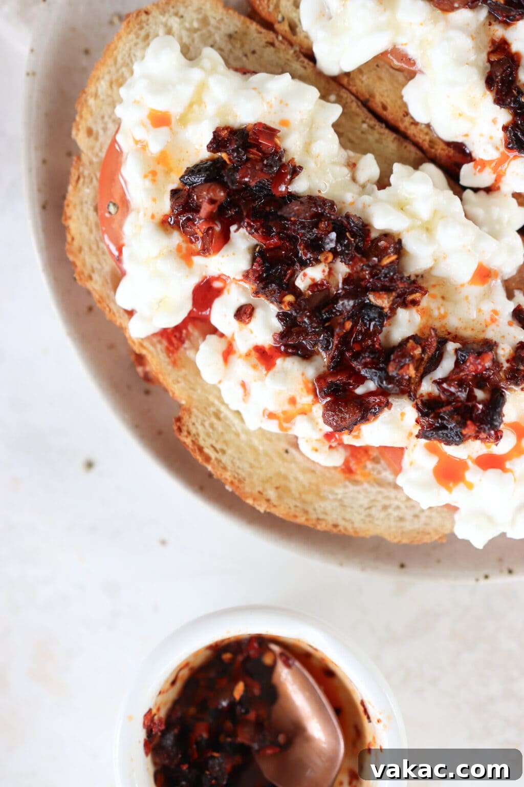 One piece of toast topped with tomato, cottage cheese, and chili crisp oil.