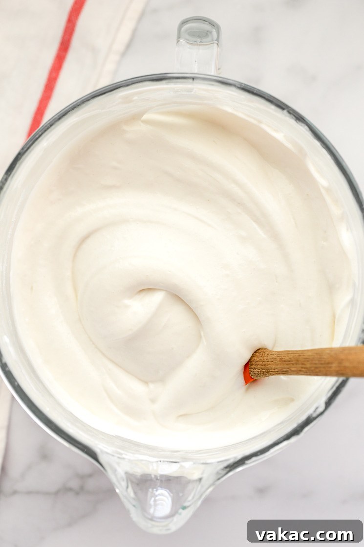 Heavenly Cloud Cake 4 Angel food cake batter inside a glass bowl with a rubber spatula resting on the side, showcasing the light, airy consistency.