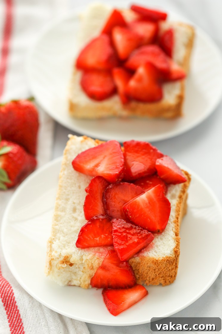 Heavenly Cloud Cake 6 Beautifully sliced angel food cake pieces on white plates, generously topped with fresh, vibrant sliced strawberries.