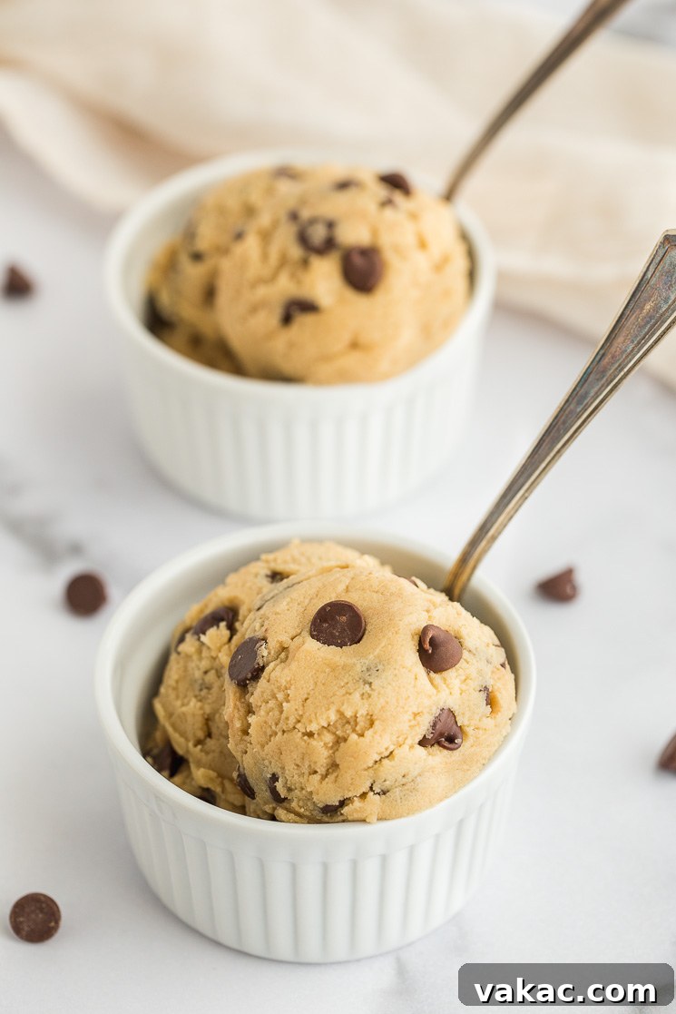 No-Bake Cookie Dough Delights 2 Two small white ramekins filled with edible cookie dough and a spoon in each one, ready to be enjoyed.