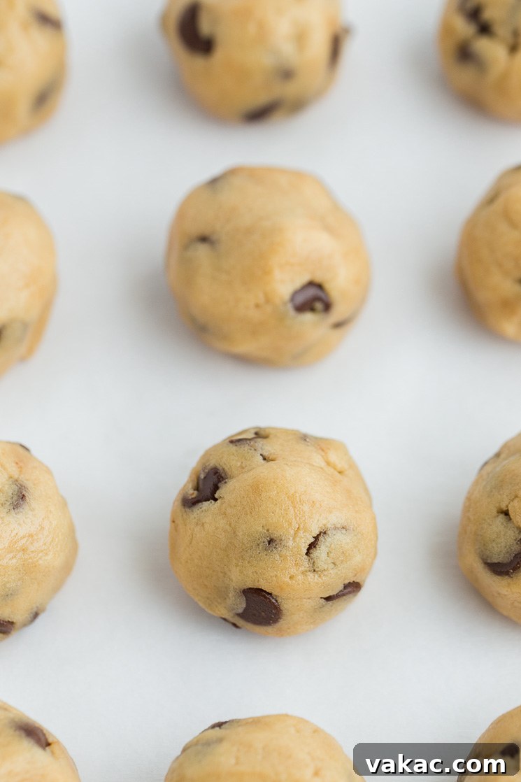 No-Bake Cookie Dough Delights 6 Edible cookie dough rolled into small, uniform balls and arranged neatly on a piece of parchment paper, ready for chilling or freezing.