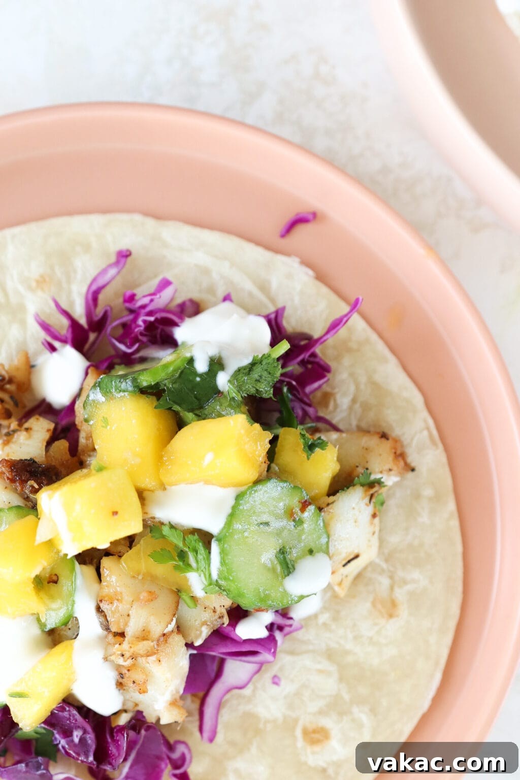 Easy 15-Minute Blackened Fish Tacos with Tangy Slaw 8 A single fish taco, artfully presented on a plate, featuring a delicious filling of cabbage, cucumber, and mango.