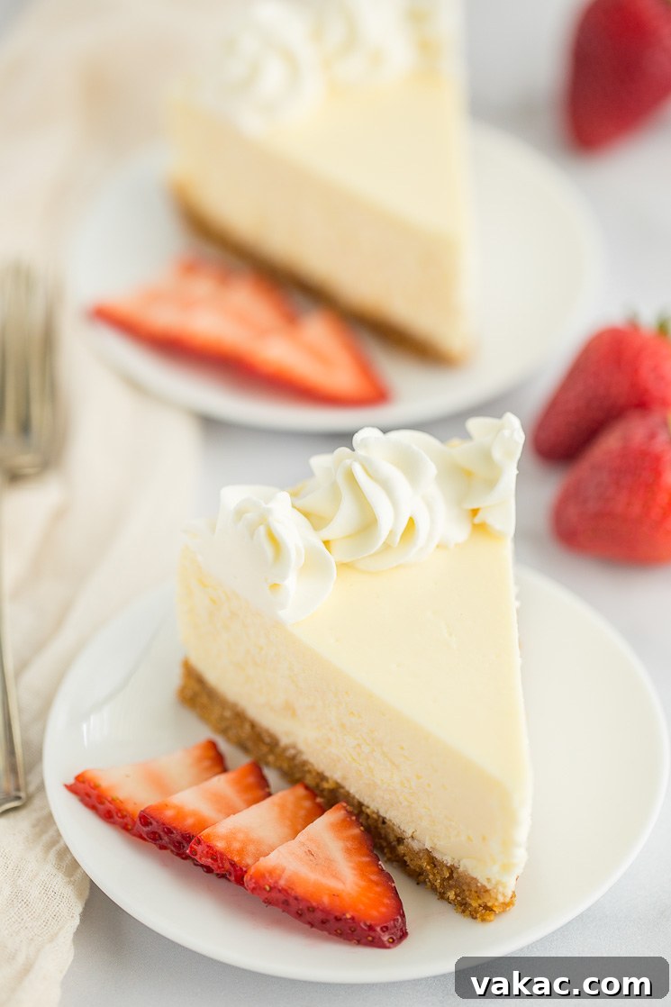 Grandma's Classic Cheesecake 6 Two slices of cheesecake on white plates with sliced strawberries on the side of each one.
