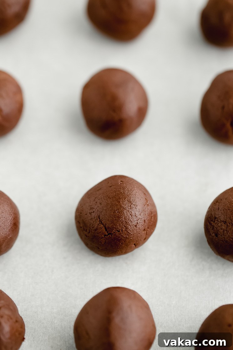 Decadent Brownie Cookies 5 Cookie dough rolled into balls on top of a piece of parchment paper.