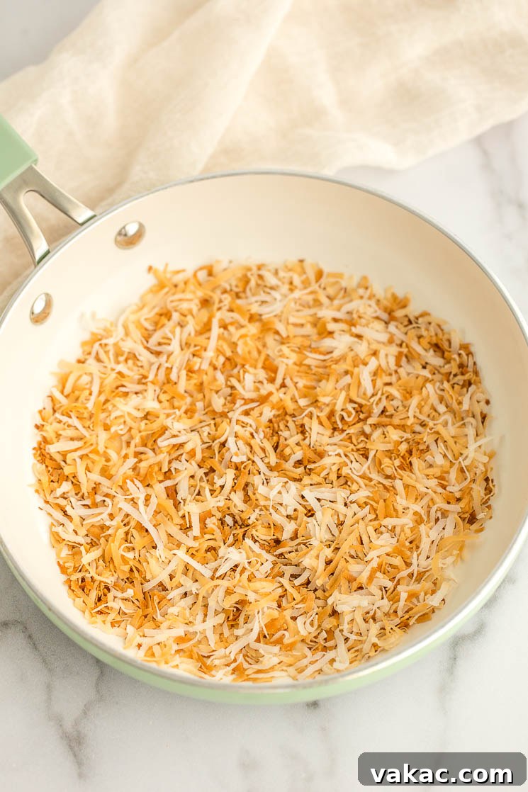 Secrets to Perfectly Toasted Coconut 5 A batch of toasted coconut in a green skillet.