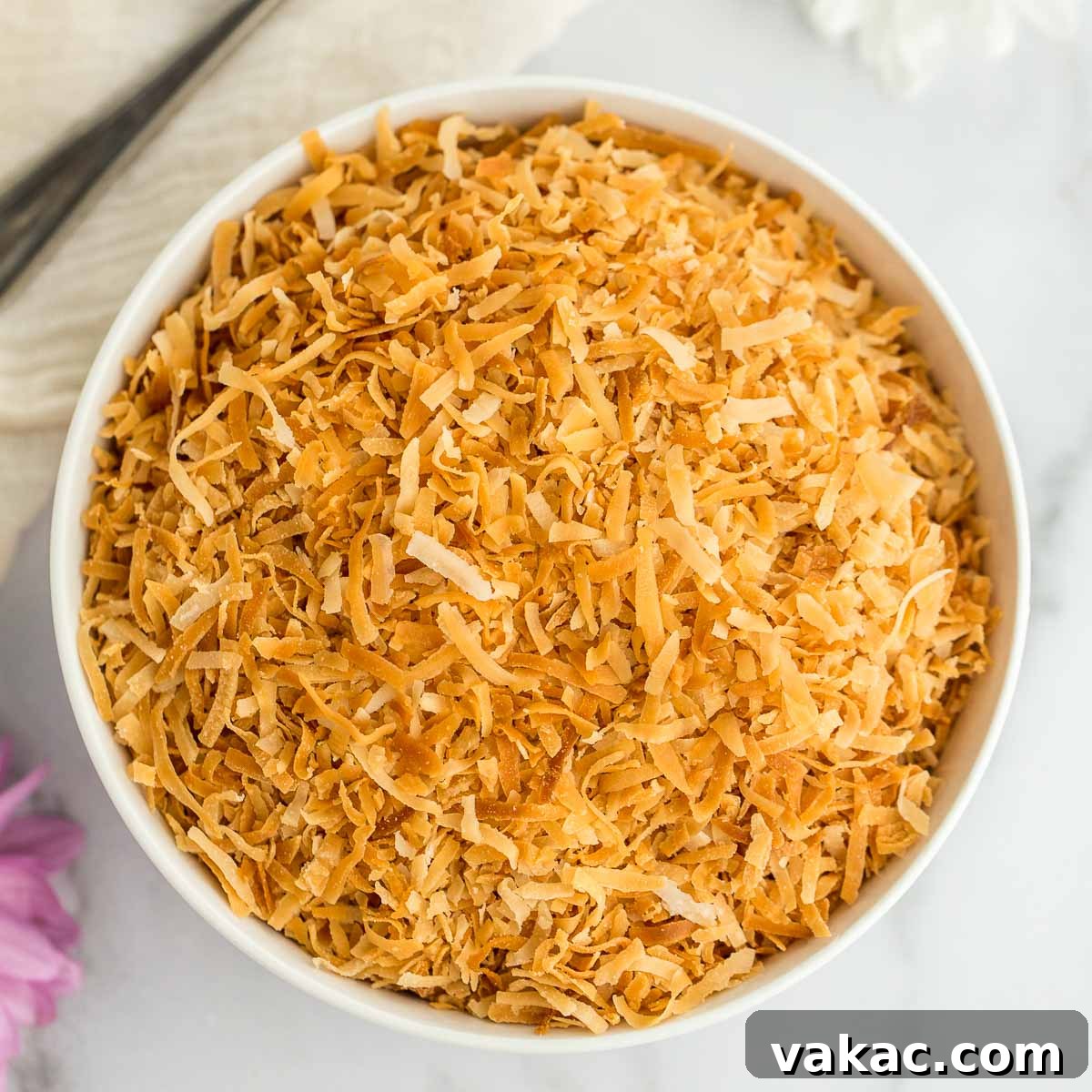 A white bowl filled with toasted coconut.