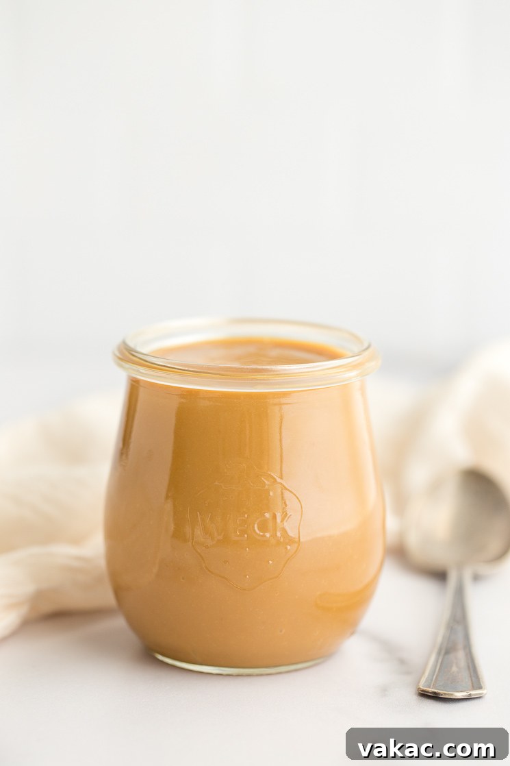 A charming glass jar filled with luscious homemade dulce de leche, resting on a pristine marble surface, inviting you to indulge.