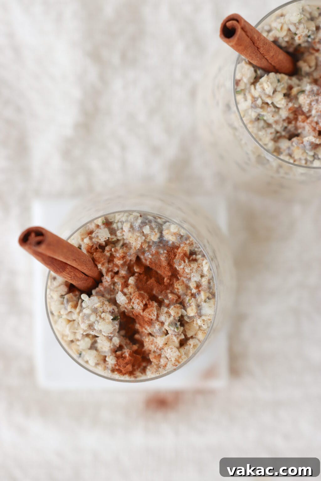 Make-Ahead Cinnamon Roll Overnight Oats 7 Two elegantly presented glasses of cinnamon roll overnight oats, adorned with cinnamon sticks, positioned on a clean white background, showcasing a wholesome and appetizing breakfast choice.