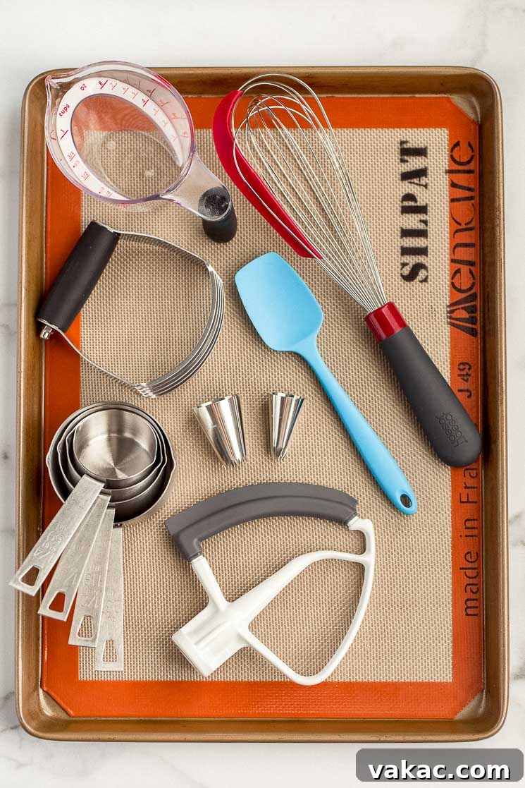The Ultimate Baking Tool Guide 2 A baking sheet displaying multiple baking tools such as a whisk, measuring cups, and piping tips.