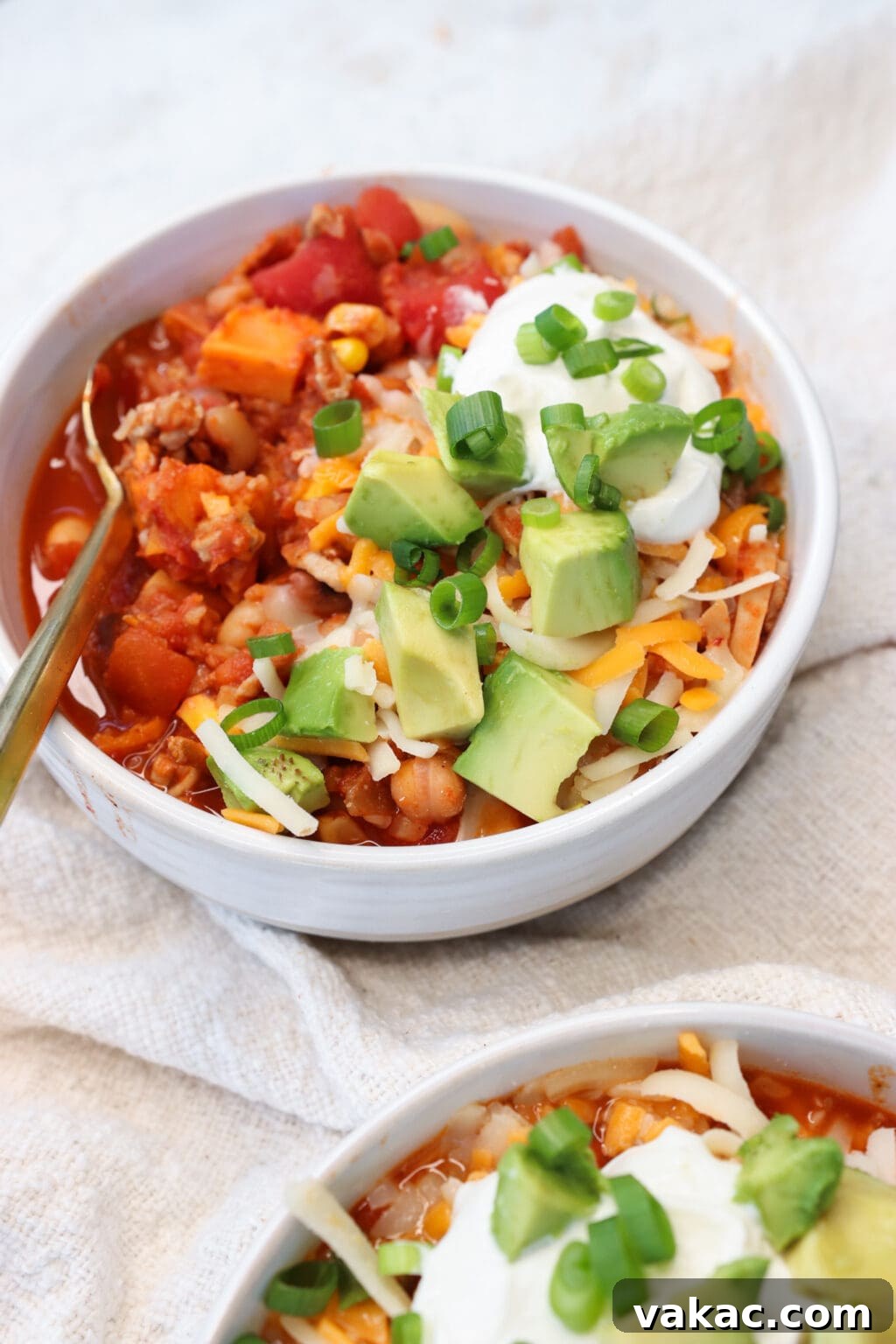 Comforting Slow Cooker Sweet Potato and Turkey Chili 7 A close-up of a bowl of Slow Cooker Sweet Potato and Turkey Chili, garnished with vibrant green cilantro and creamy avocado slices, highlighting its rich texture and appealing presentation.